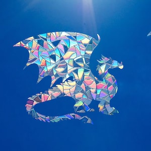 Könnte beinhalten: Eine farbige Glasmalerei-Drachen-Silhouette vor einem strahlend blauen Himmel.