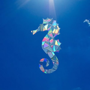Peut inclure: Une silhouette de cheval de mer en vitrail coloré sur un ciel bleu vif.