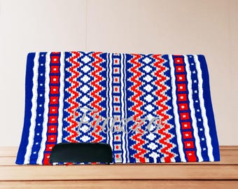 May include: A rectangular saddle pad with a vibrant pattern of red, white, and blue geometric designs. The pad features a black leather-like piece at the bottom. The word "Equestre" is embroidered in white.
