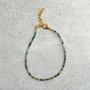 Peut inclure: Un bracelet délicat composé de petites perles de pierres précieuses facettées aux tons verts, roses et dorés, agrémenté de minuscules entretoises en métal doré. Le bijou comprend un fermoir mousqueton doré et une chaînette de réglage.