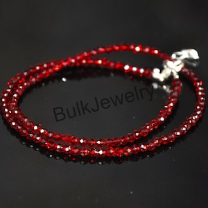 Puede incluir: Un delicado collar de cuentas rojas con un cierre plateado. El collar está hecho de pequeñas cuentas facetadas que captan la luz. Las palabras "Bulk Jewelry" son visibles en la imagen.