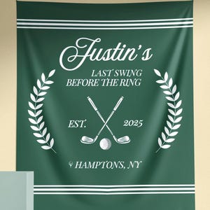 Peut inclure: Une tapisserie vert foncé avec du texte et des graphiques blancs. Le texte indique "Justin's Last Swing Before The Ring" avec des clubs de golf croisés, une balle de golf et l'année 2025. L'emplacement "Hamptons, NY" est également affiché.