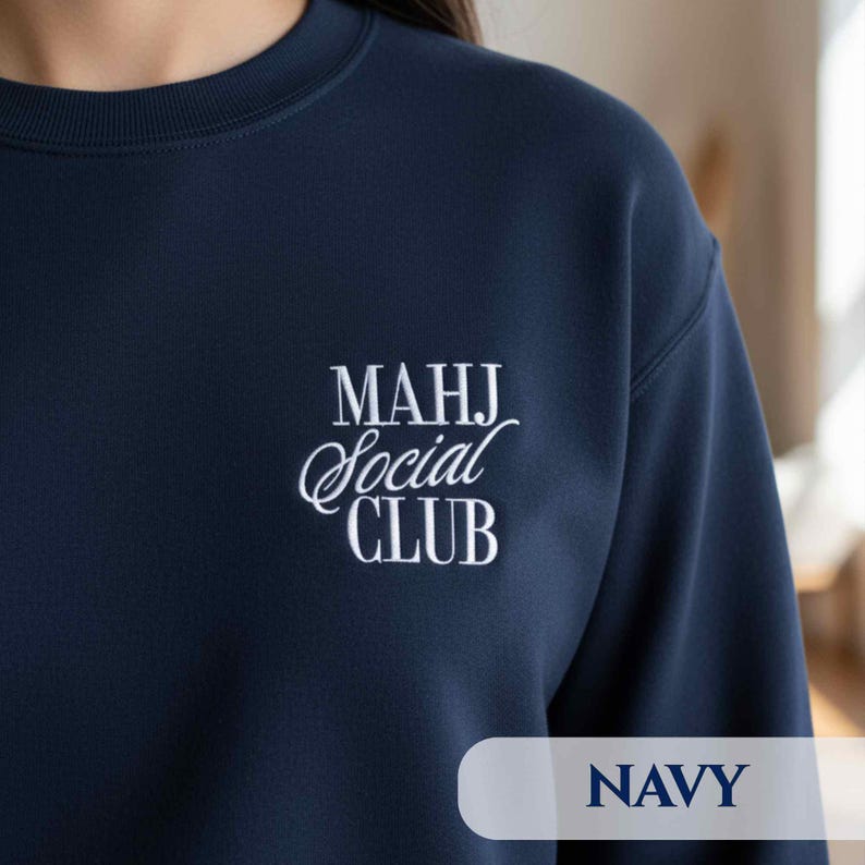 May include: Navy blue sweatshirt with the text "MAHJ Social CLUB" in white script. The word "NAVY" is printed in a sans-serif font at the bottom. The sweatshirt has a crew neck.