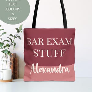 May include: A tote bag with black handles and a burgundy and pink color block design. The words "BAR EXAM STUFF" and the name "Alexandra" are printed in white. A circular graphic reads "CUSTOM TEXT, COLORS & SIZES".