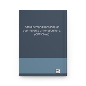 May include: A hardback journal with a two-tone design. The top section is dark blue, and the bottom is a lighter blue. Text on the cover reads, "Add a personal message or your favourite affirmation here. (OPTIONAL)." A small barcode is in the bottom right corner.
