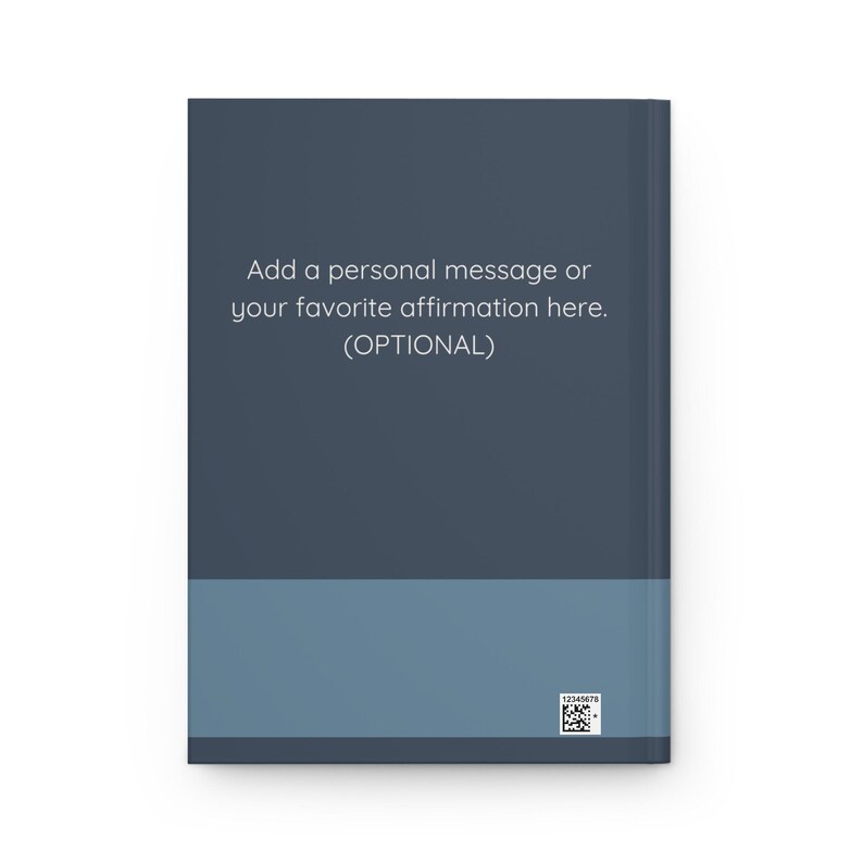 May include: A hardback journal with a two-tone design. The top section is dark blue, and the bottom is a lighter blue. Text on the cover reads, "Add a personal message or your favourite affirmation here. (OPTIONAL)." A small barcode is in the bottom right corner.