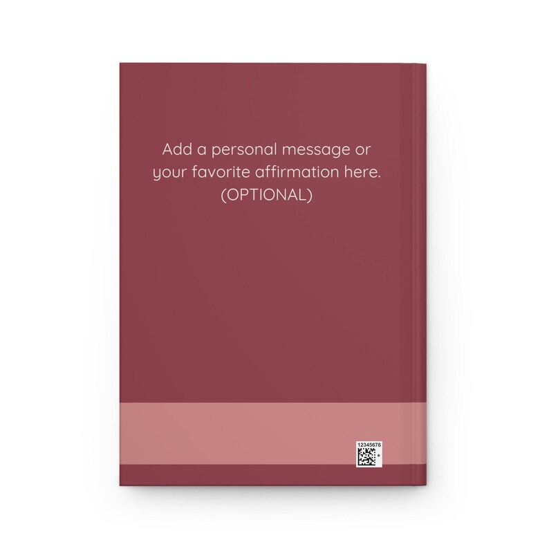 May include: A maroon journal with a light pink band at the bottom. The cover features the text: "Add a personal message or your favourite affirmation here. (OPTIONAL)." A small QR code is in the bottom right corner.