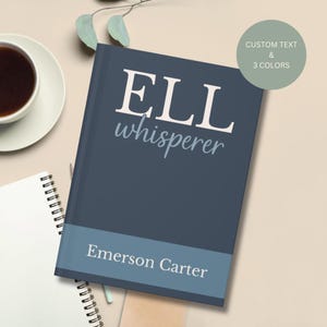 May include: A navy blue hardcover journal with the text "ELL whisperer" in white and "Emerson Carter" in a light blue banner. A cup of coffee and a spiral notebook are in the background.