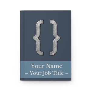 May include: A hardback notebook with a dark blue cover. The cover features a silver bracket symbol and a light blue band with the text "Your Name - Your Job Title -" in white.
