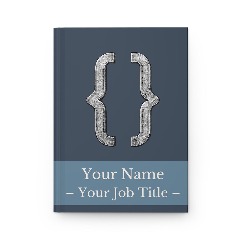 May include: A hardback notebook with a dark blue cover. The cover features a silver bracket symbol and a light blue band with the text "Your Name - Your Job Title -" in white.
