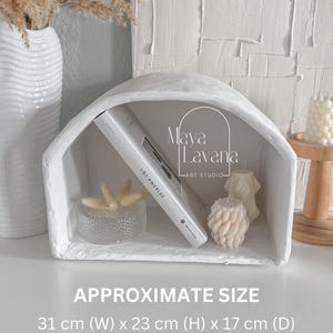 May include: White plaster shelf with a rounded arch top. The shelf is 31 cm wide, 23 cm high, and 17 cm deep. The shelf is decorated with a book, a glass bowl, and candles.