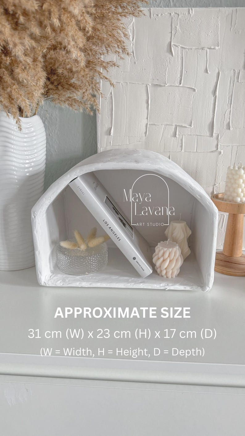 May include: White plaster shelf with a rounded arch top. The shelf is 31 cm wide, 23 cm high, and 17 cm deep. The shelf is decorated with a book, a glass bowl, and candles.