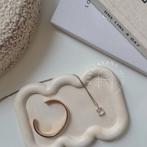 May include: A white ceramic tray with a cloud-like shape, featuring a gold bracelet and a delicate necklace with a pink gemstone pendant. The tray is labelled "MAYALAVANA ART STUDIO" and "Aesthetic Sustainable Home Decor".