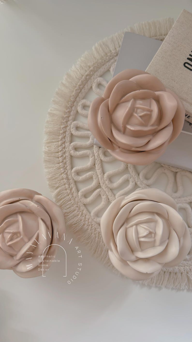 May include: Three large, beige, fabric rose flower decorations on a white, crocheted, round mat with fringe. The flowers are arranged in a semi-circle. The text "Aesthetic Sustainable Home Decor" is in the lower left corner of the image.