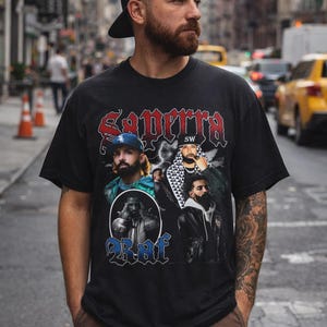 May include: Black t-shirt featuring a graphic design with the text "Saperra" in red and blue. The design includes multiple portraits of a person. The person is wearing a black cap and brown pants.