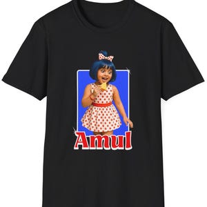 Puede incluir: Camiseta negra con un gráfico de una persona con pelo azul y un vestido de lunares sosteniendo un aperitivo. El gráfico está sobre un fondo azul con la palabra "Amul" en texto rojo y blanco.