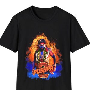 May include: Black t-shirt with a graphic of a man with blue and red face paint, wearing a necklace and standing in flames. The text "Pushpa: The Rule" is printed on the shirt.