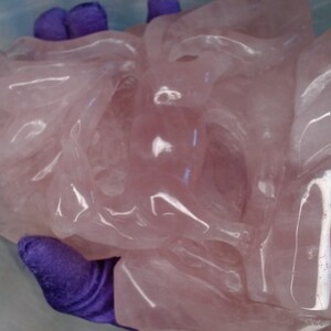May include: A large, intricately carved pink rose quartz sculpture. The sculpture is smooth and polished, with a translucent appearance.