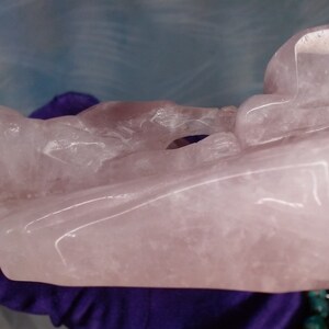 May include: A large, carved pink rose quartz sculpture. The sculpture is abstract and features a variety of shapes and textures.