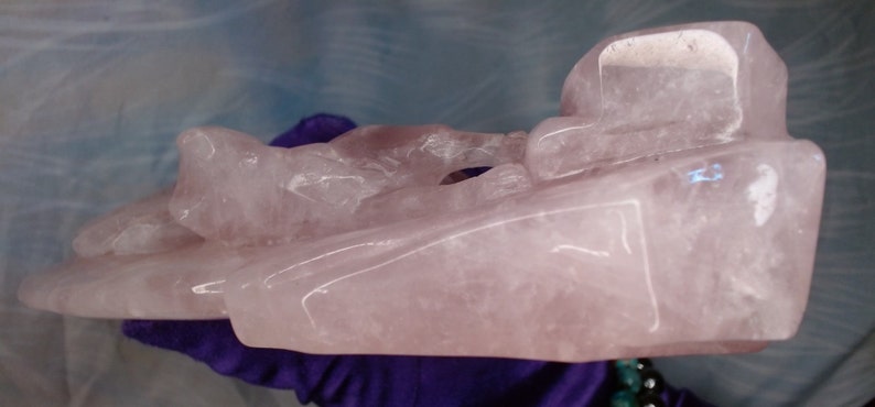 May include: A large, carved pink rose quartz sculpture. The sculpture is abstract and features a variety of shapes and textures.
