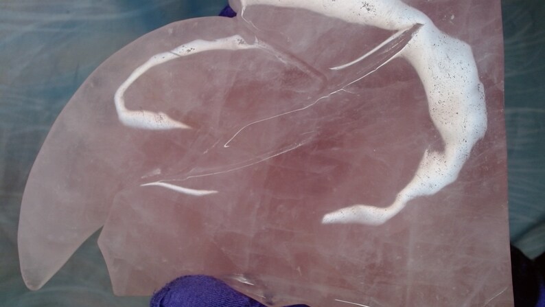 May include: A large, pink, heart-shaped piece of rose quartz with white veins and swirls. The quartz is polished and smooth.