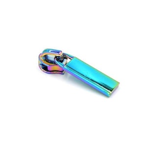 May include: A single, iridescent zipper pull with a rectangular tab. The pull is a vibrant mix of blues, greens, and purples, creating a rainbow effect. The zipper pull is set against a plain white background.