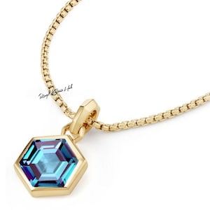 May include: A gold chain necklace with a hexagonal pendant featuring a blue gemstone.