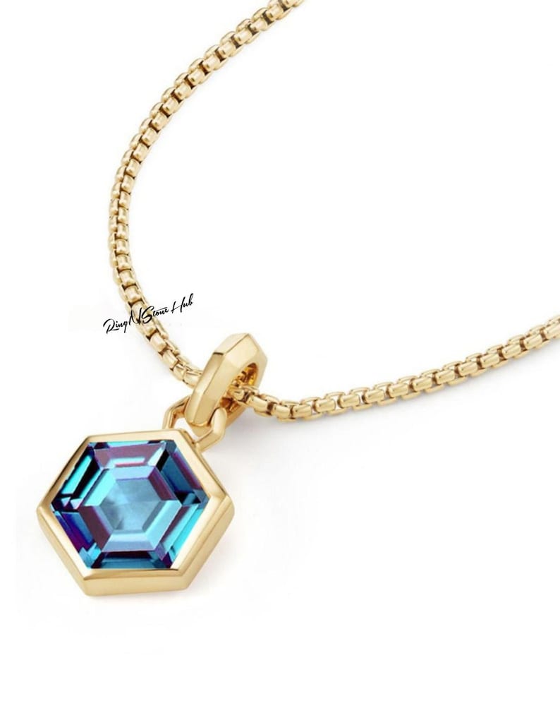 May include: A gold chain necklace with a hexagonal pendant featuring a blue gemstone.