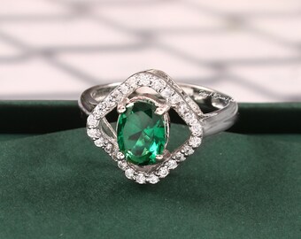 Puede incluir: Un anillo de plata con una gran piedra preciosa verde de forma ovalada rodeada de pequeñas piedras preciosas transparentes.