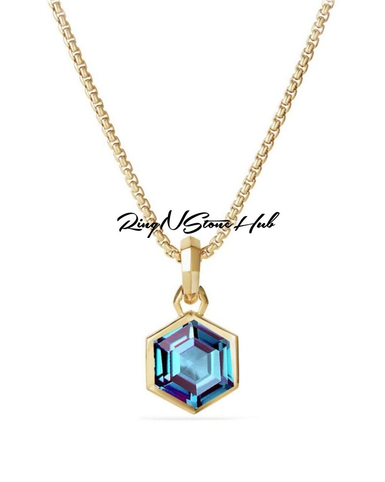 May include: A gold chain necklace with a hexagonal pendant featuring a blue gemstone.