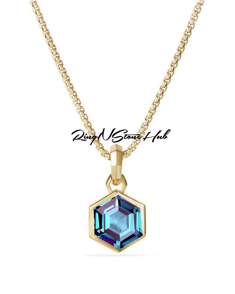 May include: A gold chain necklace with a hexagonal pendant featuring a blue gemstone.