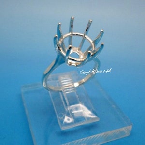 Puede incluir: Engaste de anillo de plata con bisel redondo y seis garras. El engaste está en un expositor de plástico transparente.