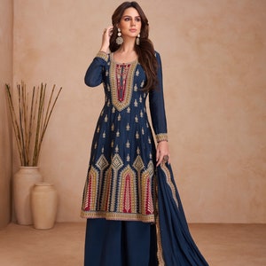 Puede incluir: Un traje de pantalón palazzo azul marino con bordados dorados. La parte superior tiene un escote redondo y mangas largas. Los pantalones tienen una pierna ancha y llegan al tobillo. El traje se combina con una dupatta a juego.