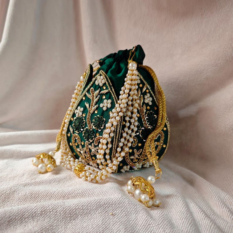 A model wearing an ethnic outfit holds the green floral potli bag at her side, perfect for festive occasions.