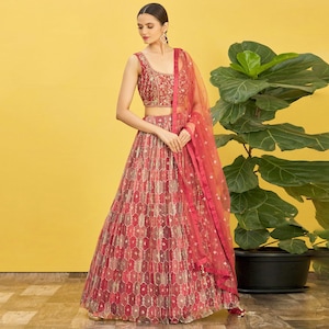 May include: A red and gold embroidered formal dress with a matching sheer scarf. The sleeveless top and skirt feature intricate patterns. The dress is a traditional Indian style, suitable for special occasions.