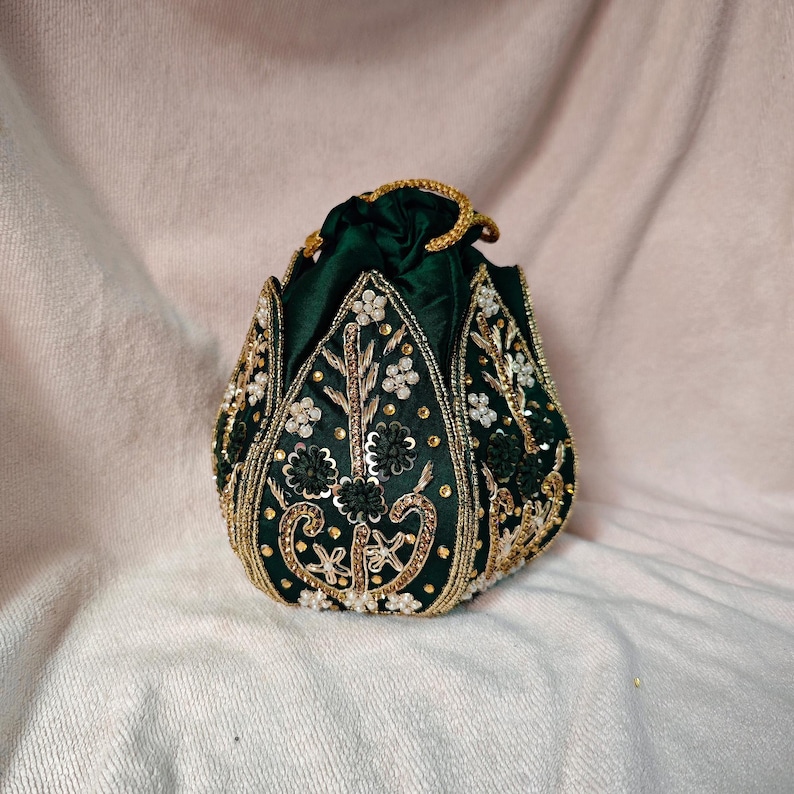 Detailed macro shot of the gold threadwork and the dark green base of the lotus clutch bag.