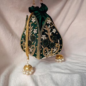 An angled shot of the dark green potli bag, emphasizing the depth of its blackish-green tone and gold motif.