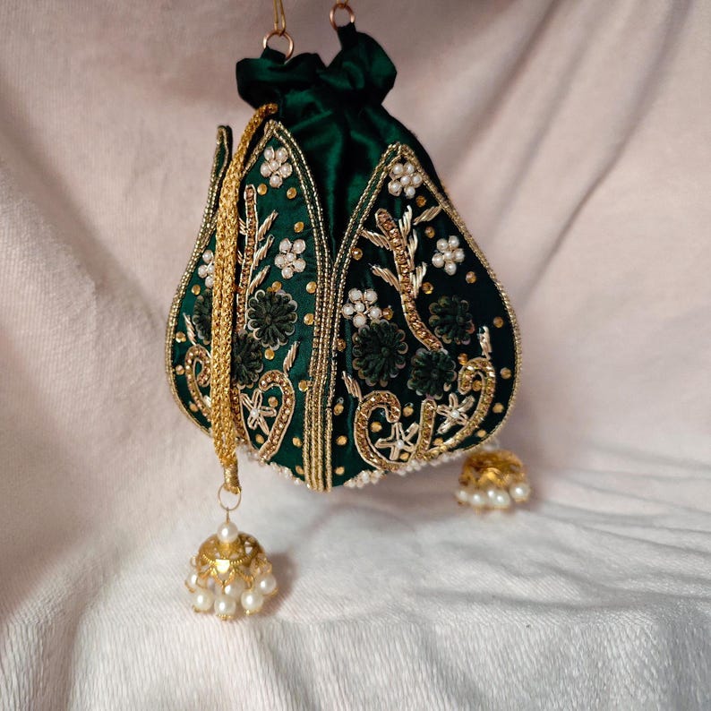 An angled shot of the dark green potli bag, emphasizing the depth of its blackish-green tone and gold motif.