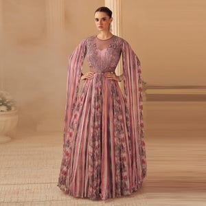 May include: A floor-length, pleated gown in shades of pink, red, and brown with a floral pattern. The dress features a sheer neckline and long, flowing sleeves. The bodice is embellished with intricate embroidery.