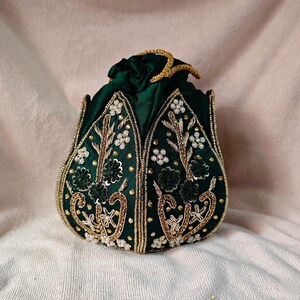 Back view of the green lotus potli bag, showing the rich texture of the dark green silk fabric.