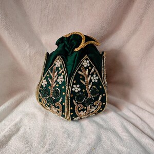 Styled photoshoot of the dark green potli bag with Indian sweets and candles, ideal for a gift for her.