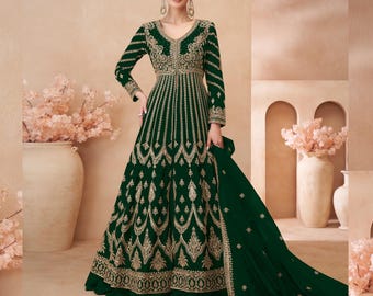 Puede incluir: Un vestido verde largo hasta el suelo con bordados dorados y un dupatta a juego. El vestido tiene un escote en V y mangas largas.