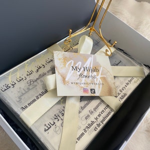 Może przedstawiać: Białe pudełko prezentowe ze złotym stojakiem i stos białych kartek z kaligrafią arabską i tekstem "My Hijab Flowers" i "Bismillahi walay Au nom d'Allah".