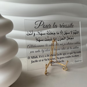 Może przedstawiać: Przezroczysty znak akrylowy z złotą podstawką, przedstawiający muzułmańską modlitwę w języku arabskim i tłumaczenie na język francuski. Tekst brzmi "Pour la réussite" (Dla sukcesu) i zawiera modlitwę "Allâhoumma lá sahla illâ mâ ja altahou sahlan. wa anta taj alou-l-hazna idha shi ta sahlan." Tłumaczenie na język francuski brzmi "Ô Allah, il n'y a de chose facile que ce que Tu rends facile et si Tu le veux, Tu peux rendre la chose difficile facile."