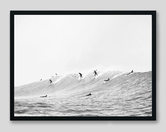 May include: Black and white photograph of surfers riding waves. The surfers are silhouetted against the bright sky and the water is choppy.