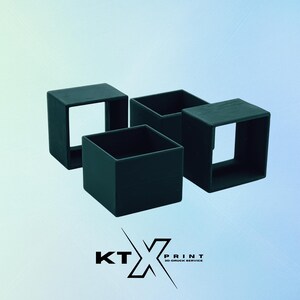 Könnte beinhalten: Vier schwarze, quadratische Objekte mit offenen Ober- und Seitenflächen sind vor einem Farbverlaufshintergrund angeordnet. Die Objekte scheinen hohle Würfel zu sein. Das Logo "KT PRINT 3D-DRUCK SERVICE" ist unten sichtbar.