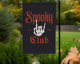 Puede incluir: Una bandera de jardín negra con el texto "Spooky Club" en letras rojas y blancas. El texto "Est 1693" está en letras blancas debajo de la palabra "Spooky" y una mano de esqueleto blanca está haciendo un gesto de rock and roll entre las palabras "Spooky" y "Club".