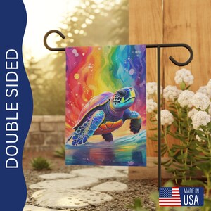 May include: Double-sided garden flag featuring a vibrant, watercolor-style sea turtle against a rainbow background. The flag is displayed on a black metal stand, with the text "DOUBLE SIDED" on the left side. The flag is made in the USA.