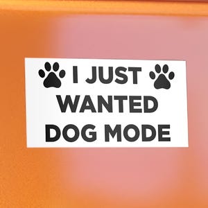 May include: White sticker with black text and paw prints that reads "I just wanted dog mode".