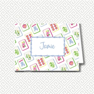 May include: A personalized card featuring a Mahjong tile pattern in green, pink, and yellow on a white background. The card has a blue bamboo-style border around the name "Jamie" in light blue.